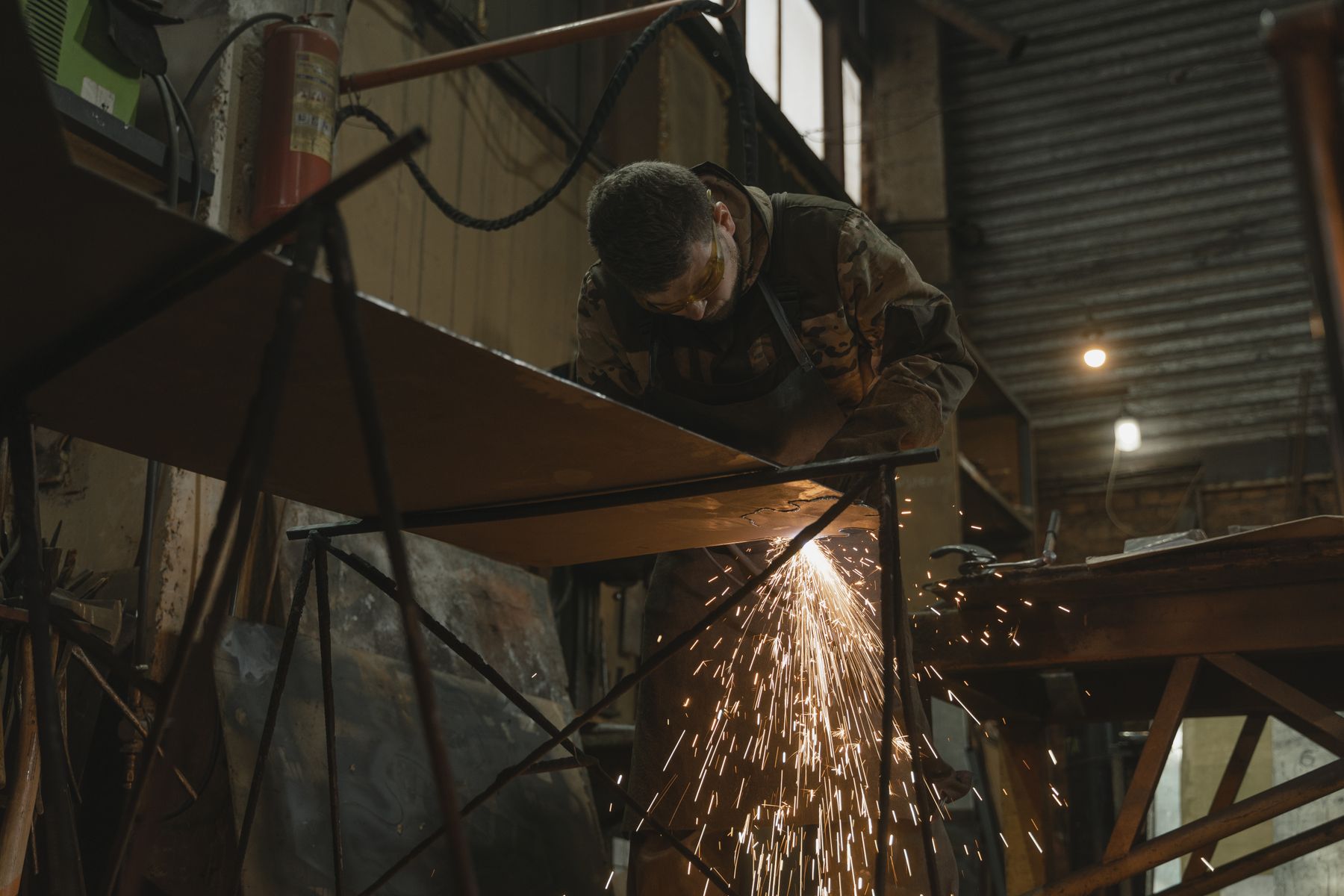 Fabricator grinding sparks off heavy steel in a trailer shop